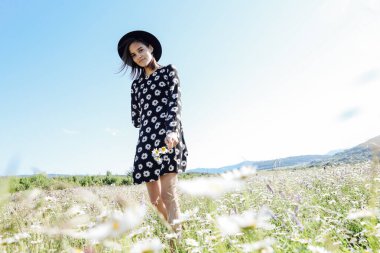 Güzel bir kadın papatya tarlasında yürüyor.