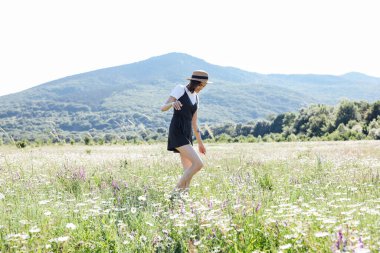 Güzel bir kadın papatya tarlasında yürüyor.