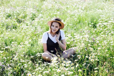 Güzel bir kadın papatya tarlasında yürüyor.