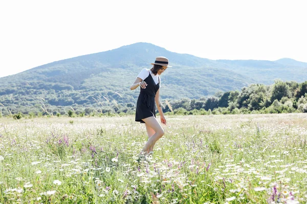 Güzel bir kadın papatya tarlasında yürüyor.