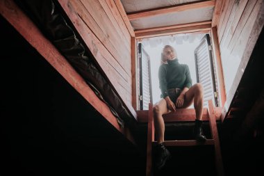 Güzel sarışın kadın çatı katının merdivenlerinde.