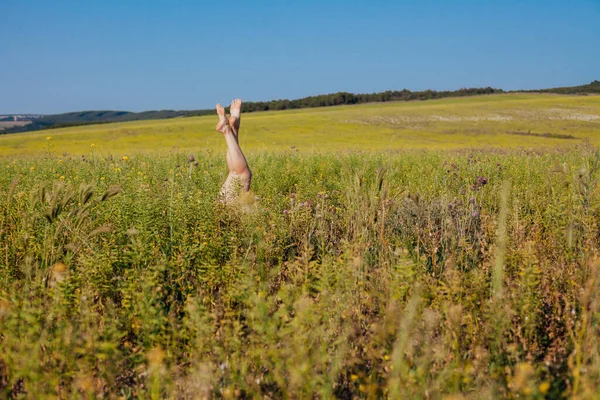Slanke vrouwelijke benen klommen uit het gras — Stockfoto