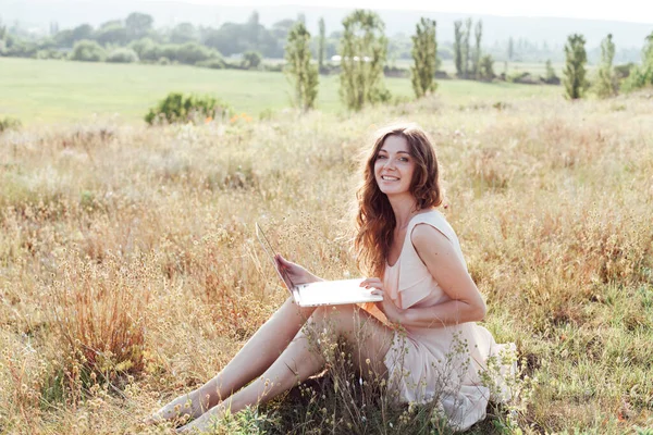 Beautiful woman working on laptop remotely in nature Royalty Free Stock Images
