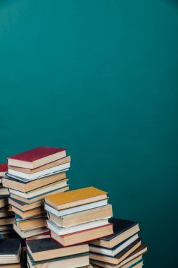 Kütüphanede öğrenmek için yeşil arka planda bir yığın eski kitap