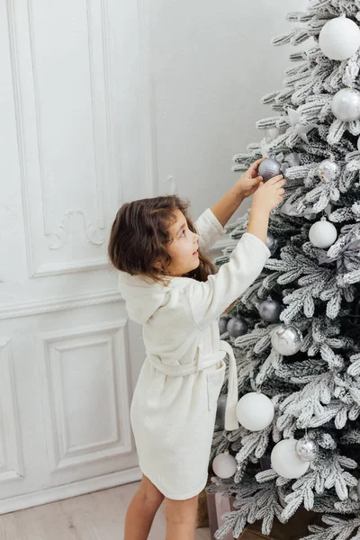 Mała kręcone dziewczyna dekoruje choinkę z prezentów nowy rok światła girlanda — Zdjęcie stockowe