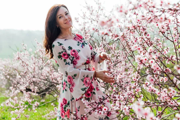 Belle femme dans une robe de printemps dans une roseraie fleurie — Photo