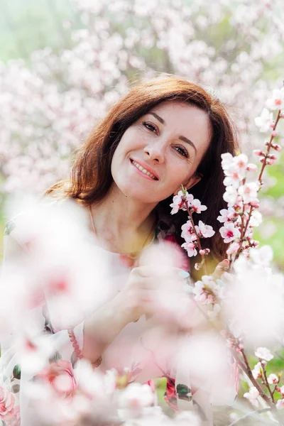 Bela mulher em um vestido de primavera em um jardim de rosas florescendo — Fotografia de Stock