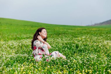 Çiçekli bahçede yeşil çimenli bahar elbisesi içinde güzel bir kadın.