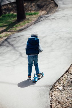 Sokakta scooter süren güzel bir çocuk.