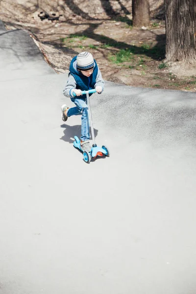 Lindo menino montando uma scooter na rua — Fotografia de Stock