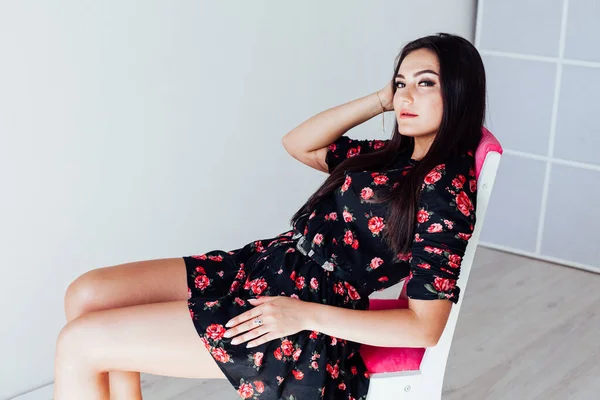 Schöne brünette Frau im schwarzen Kleid mit Blumen — Stockfoto