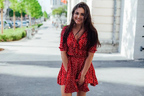 Krásná brunetka žena v červených letních šatech kráčí po ulici — Stock fotografie