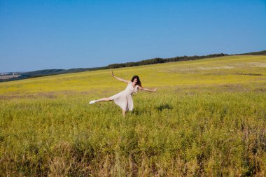 Yazlık elbiseli güzel bir kadın tarlada yürüyor.