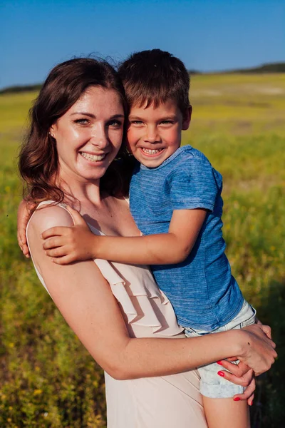 Mamá abraza a su hijo en el campo en un paseo — Foto de Stock