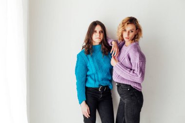 İki kız arkadaş, evde birbirlerinin yanında, sıcak kıyafetler içinde.