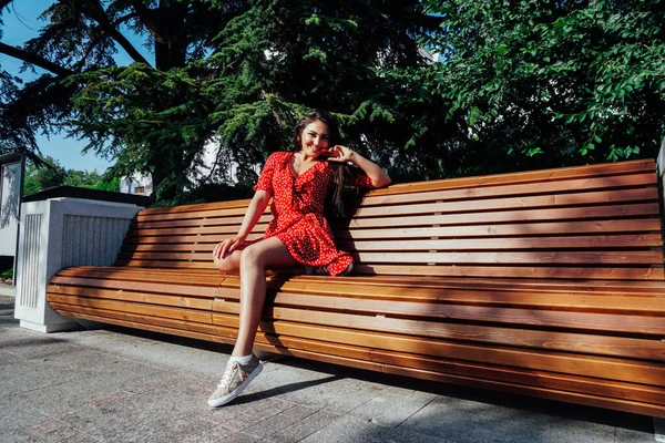 Hermosa mujer morena en un vestido rojo de verano camina por la calle —  Fotos de Stock