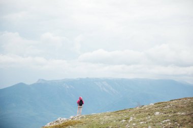 Dağın tepesinde bir kadın güzel bir manzaraya bakar.