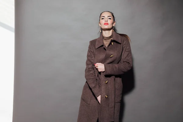 Жінка в теплому коричневому пальто на сірому фоні — стокове фото