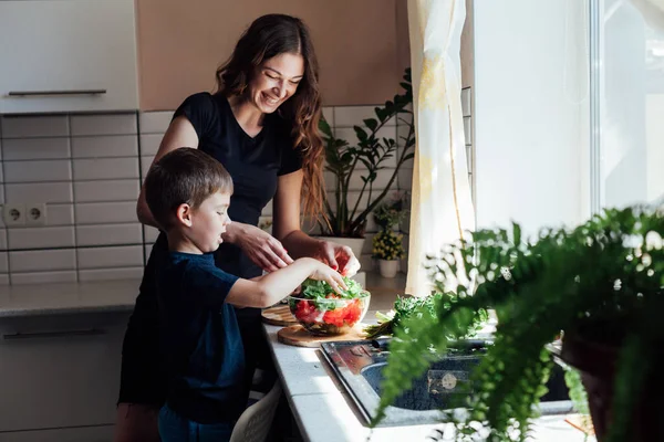 Mutter und Sohn bereiten in der Küche einen Gemüsesalat zu — Stockfoto