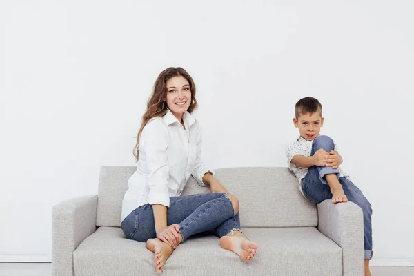 Madre e figlio si siedono sul divano grigio della casa — Foto Stock