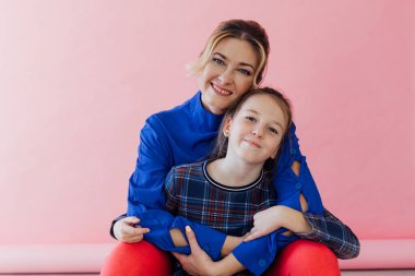 Anne ve kızı gülümseyen aile mutluluğunu kucaklıyor.