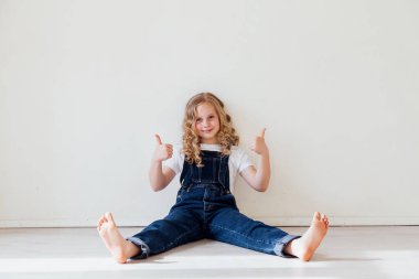 Küçük kız başparmağını beyaza gösteriyor.