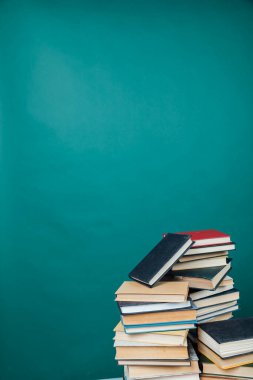 Üniversite kütüphanesinde okumak için yeşil arka planda eğitim kitapları