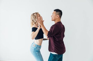 Bir kadın ve bir adam beyaz bir salonda Bachata 'nın müziğiyle dans ediyorlar.