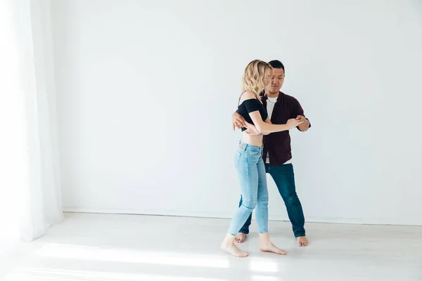 Uma mulher e um homem dançando à música de um bachata em um salão branco — Fotografia de Stock