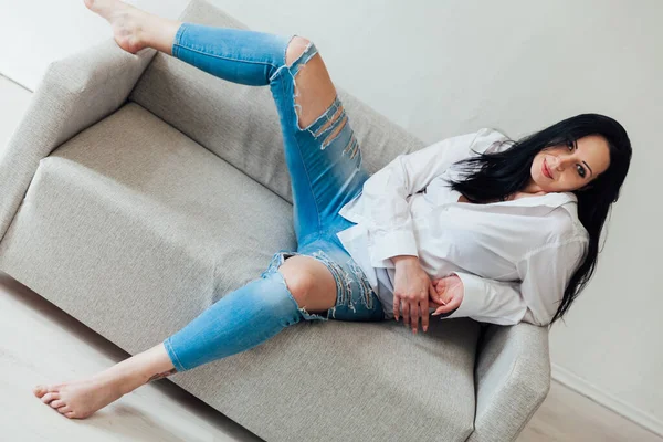 Krásná brunetka žena v domácím oblečení na gauči — Stock fotografie