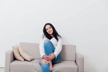 Güzel esmer kadın, kanepenin üzerinde ev kıyafetleri içinde.