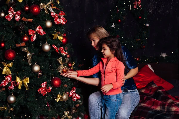 Девушка и мама украшает елку подарками новогодние гирлянды — стоковое фото