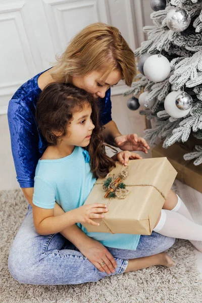 Kız ve anne Noel ağacını hediyelerle süslüyor. Yılbaşı süsleri.