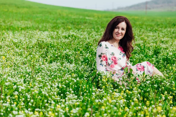 Bela mulher em um vestido de primavera em um jardim florescente com grama verde — Fotografia de Stock