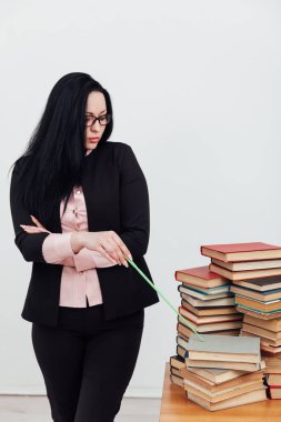 Masadaki bayan öğretmen, üniversitede okumak için kitaplarla birlikte.