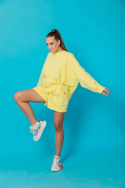 Bella donna in giallo abbigliamento sportivo su sfondo blu — Foto Stock