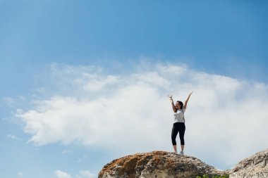 Dağın tepesinde tek başına gezen turist kadın manzaraya bakıyor.
