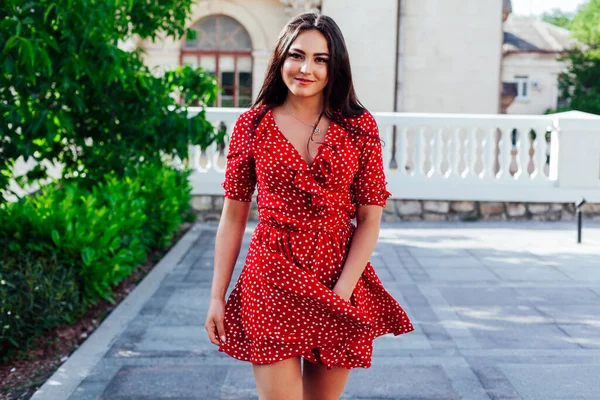 Hermosa mujer morena en un vestido rojo de verano camina por la calle — Foto de Stock