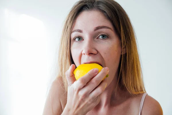 Bela loira mulher comer amarelo azedo limão — Fotografia de Stock