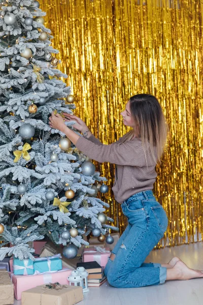 Красивая женщина украшает елку новогодними подарками — стоковое фото