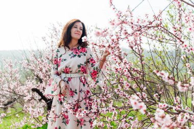 Çiçekli bir gül bahçesinde bahar elbisesi içinde güzel bir kadın.