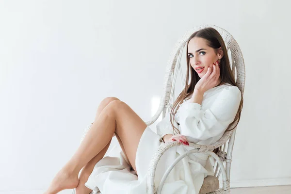 Yazlık elbisesi olan güzel bir kadın beyaz bir sandalyede oturuyor. — Stok fotoğraf