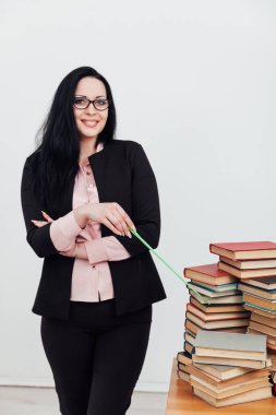 Öğrenim kitaplarıyla üniversite masasında kadın öğretmen.