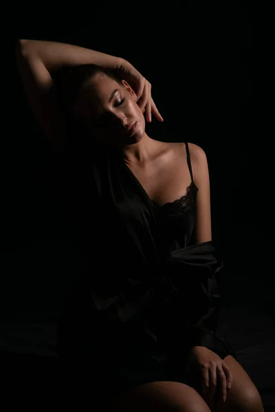 Bella donna in biancheria intima di seta nera al buio — Foto Stock