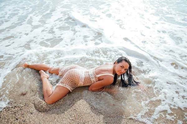 Bela mulher bronzeada em um vestido de verão na praia tomando banho no mar — Fotografia de Stock