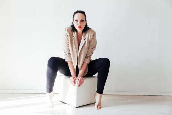 Mooie brunette vrouw in kleding en ondergoed in een witte kamer — Stockfoto