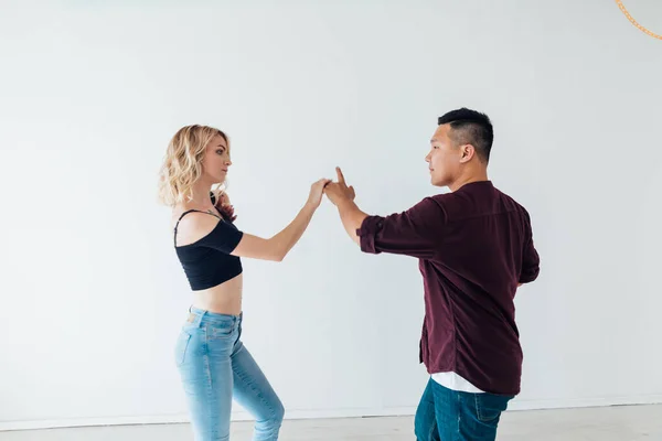 Женщина и мужчина танцуют под музыку бачаты в белом зале — стоковое фото