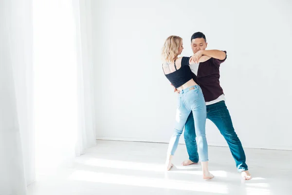 Uma mulher e um homem dançando à música de um bachata em um salão branco — Fotografia de Stock
