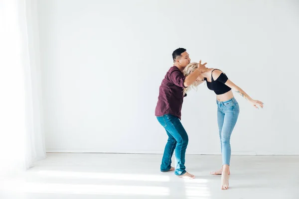 Женщина и мужчина танцуют под музыку бачаты в белом зале — стоковое фото