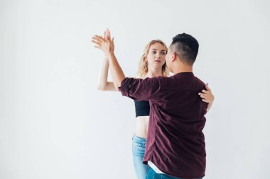 Bir kadın ve bir adam beyaz bir salonda Bachata 'nın müziğiyle dans ediyorlar.